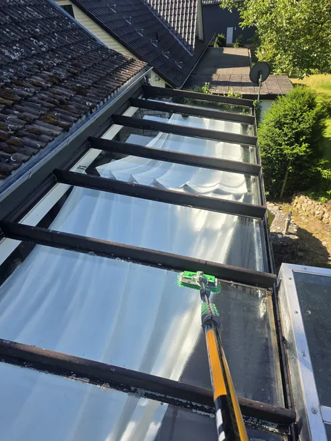 Glasdachreinigung mit Teleskopstange und Bürste an einer Terrassenüberdachung